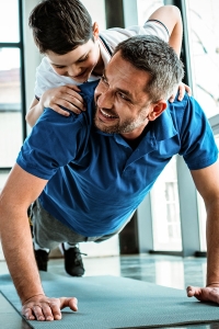 man doing push ups with child on his back after hernia surgery